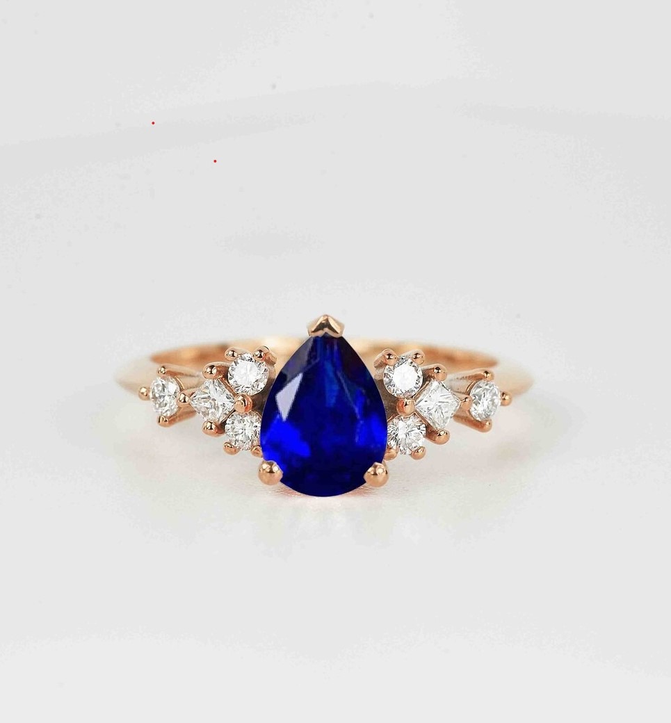 This pear cut blue sapphire ring featuring 8 x 6mm blue sapphire and princess, round diamonds. A vintage inspired cluster engagement ring.