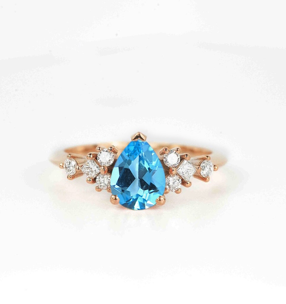 This beautiful pear cut blue topaz bridal ring comes with a center 1.50ct blue topaz and white natural diamonds. Available in rose gold, yellow gold, white gold, or platinum.