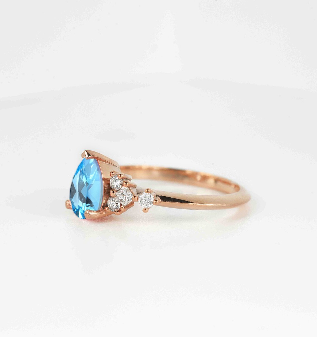 This beautiful pear cut blue topaz bridal ring comes with a center 1.50ct blue topaz and white natural diamonds. Available in rose gold, yellow gold, white gold, or platinum.