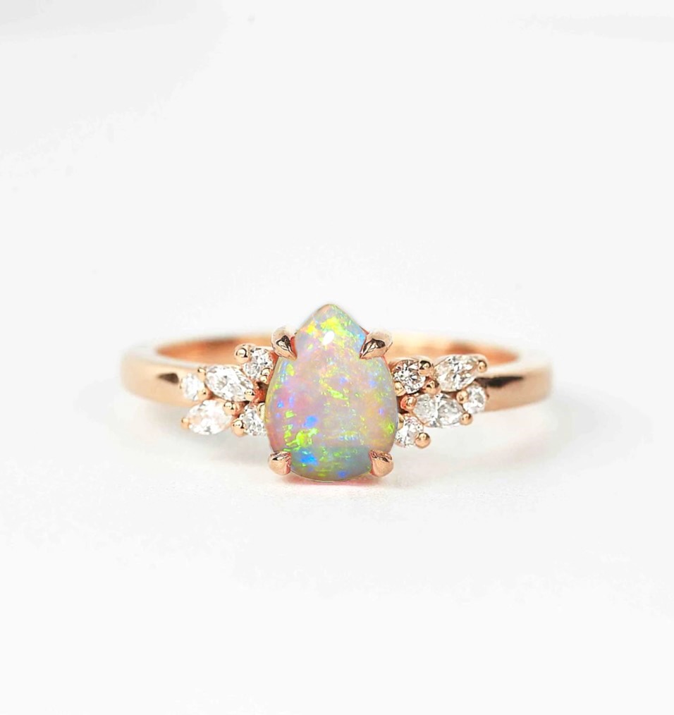 Opal and diamond cluster anniversary ring with 8 x 6mm opal and white accent diamonds. The unique design of this art deco style ring comes with solid 9k,14k or 18k gold or platinum.