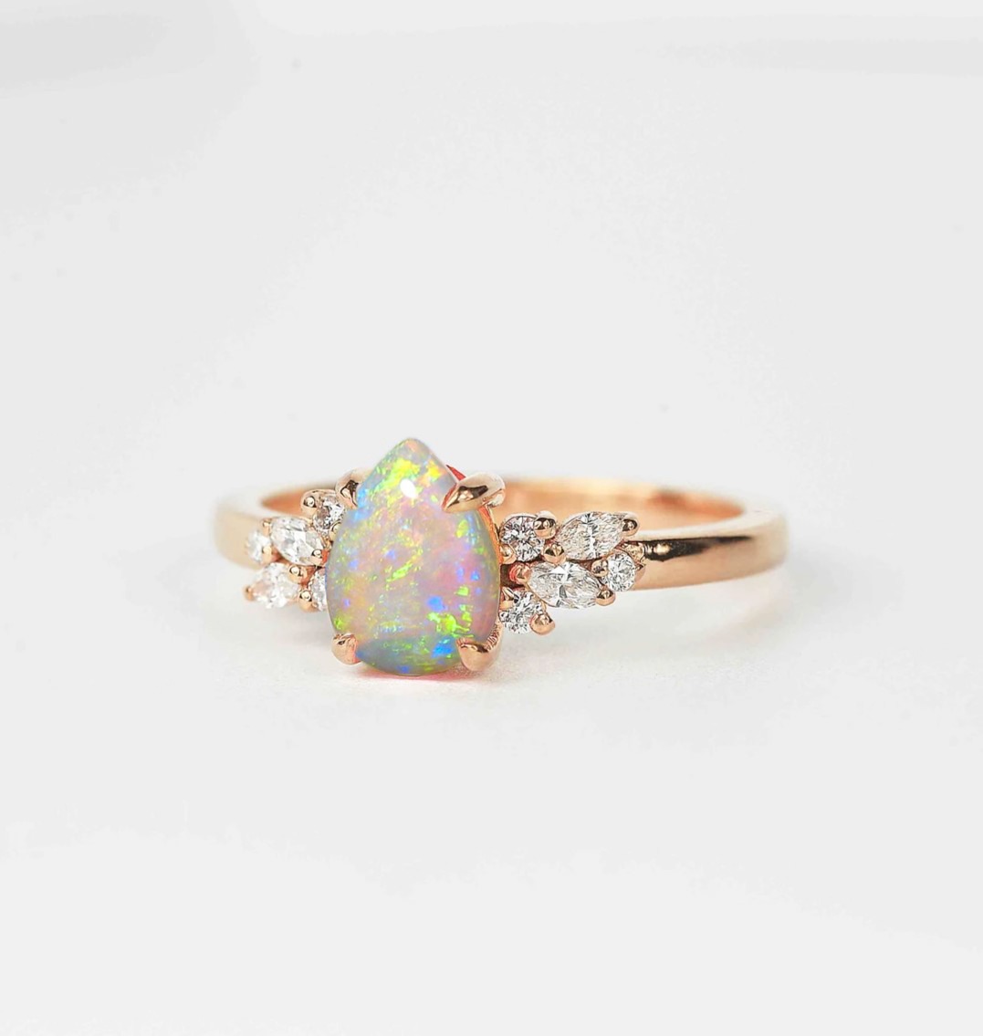 Opal and diamond cluster anniversary ring with 8 x 6mm opal and white accent diamonds. The unique design of this art deco style ring comes with solid 9k,14k or 18k gold or platinum.